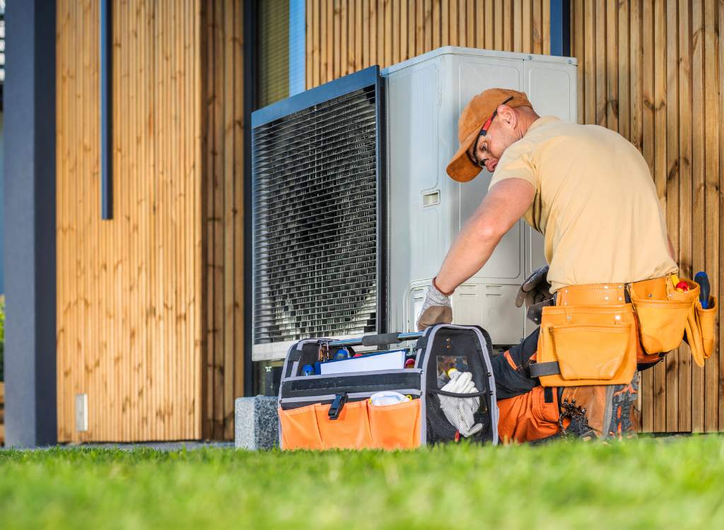Installateur bei der Montage einer Wärmepumpenanlage im Außenbereich eines Hauses
