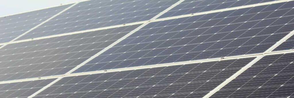 Nahaufnahme mehrerer Photovoltaikmodule in Reihen unter klarem Himmel.