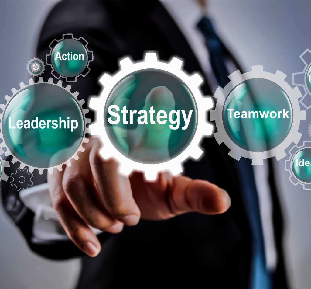 Geschäftsperson zeigt auf digitale Zahnräder mit Begriffen wie Strategy, Leadership und Teamwork.