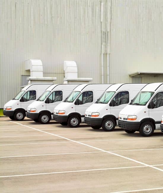 Firmenfuhrpark mit Transportern vor einem Gewerbebetrieb